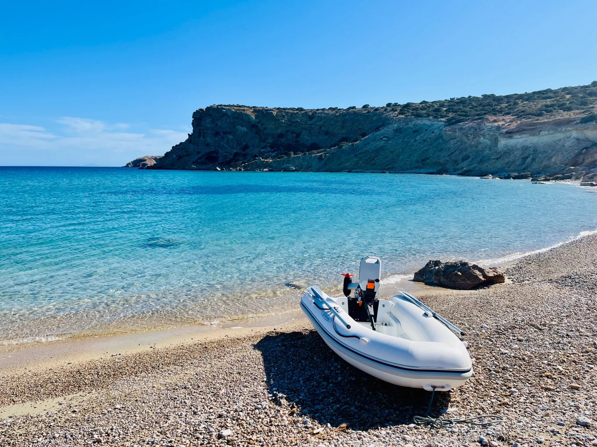 Dinghy with electric outboard on a secluded Greek beach